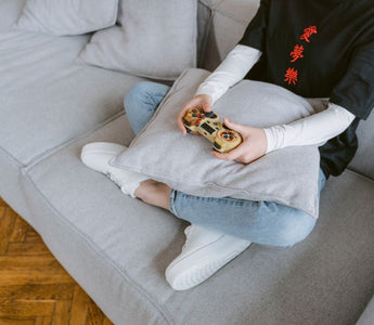 Person sitting on a couch playing video games, symbolizing leisure and entertainment.
